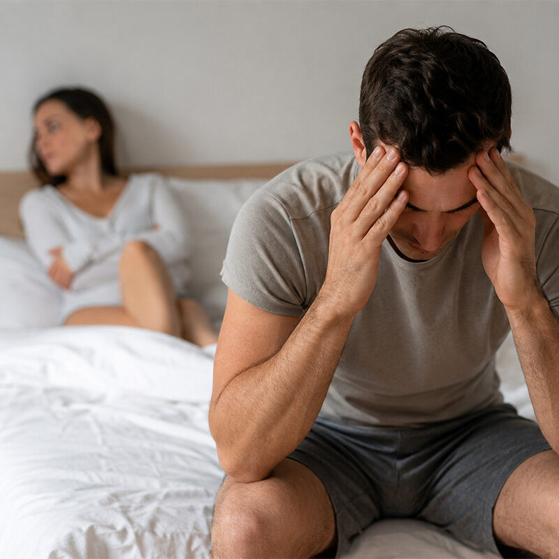 Man experiencing Erectile Dysfunction with emotional stress and relationship concerns in a bedroom setting
